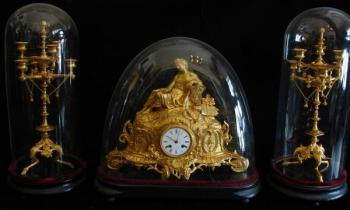 The bronze clock with candlesticks under glass bel